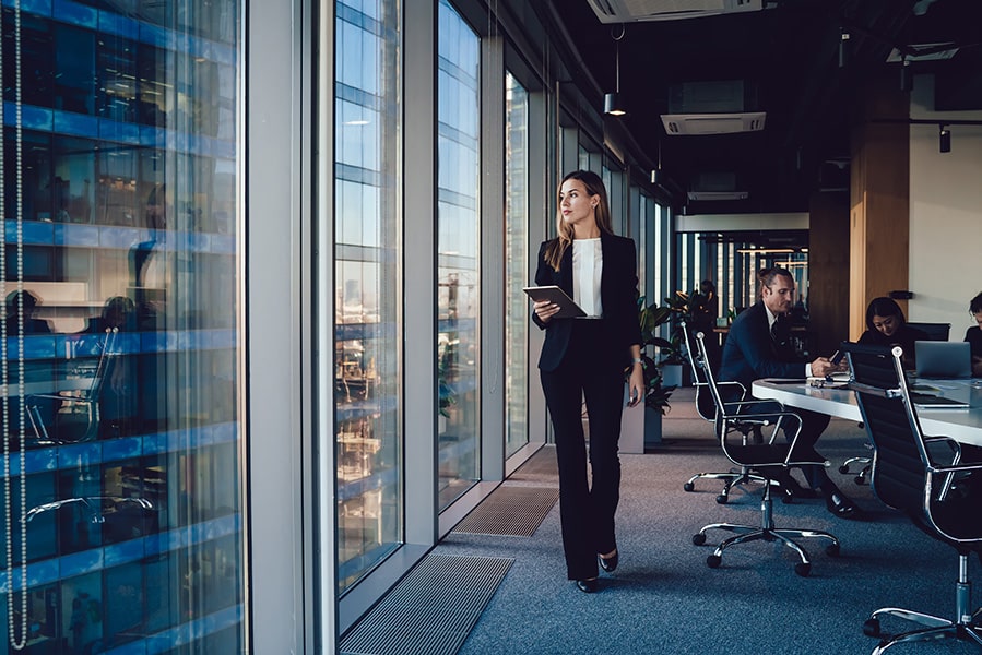 A businesswoman walking with a tablet at the office.