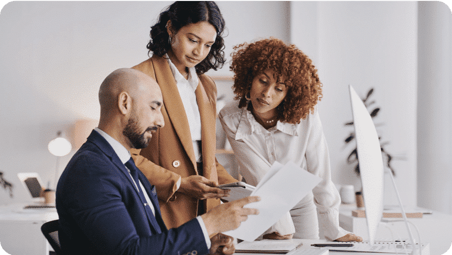 Three employees looking at documents together.