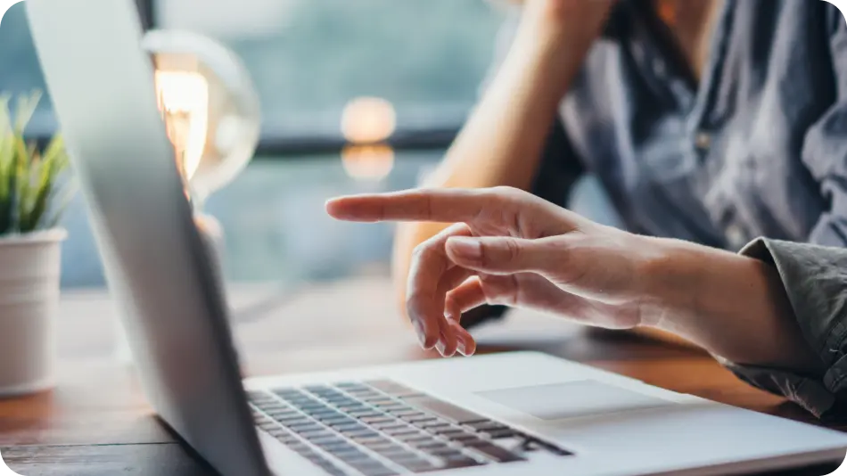 Hand, pointing at revenue recognition data on the laptop.
