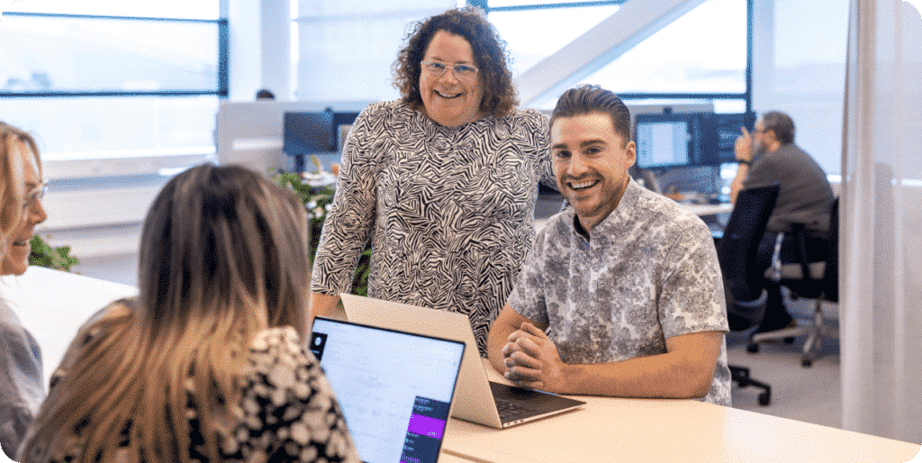 Accounts payable team collaborating around a laptop in a modern office.
