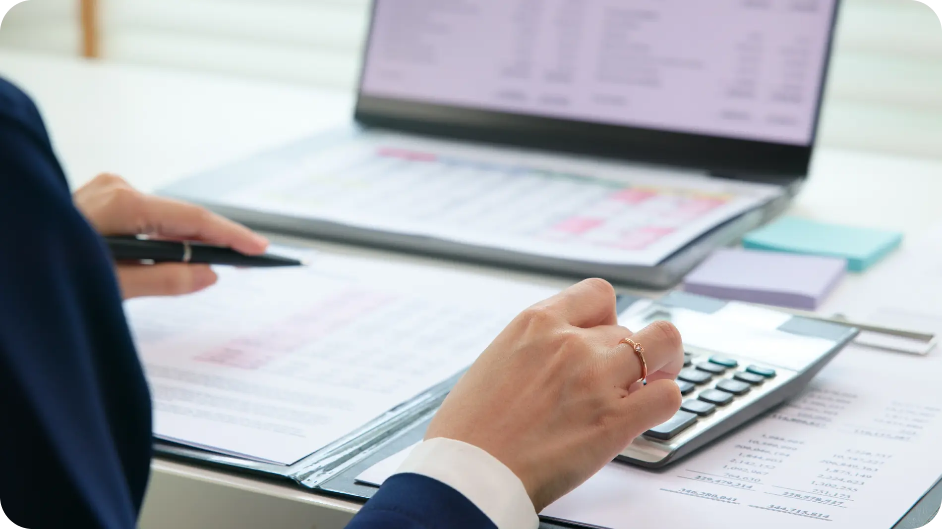 Close-up of a person using a calculator and reviewing financial spreadsheets, emphasizing budget control and financial planning.