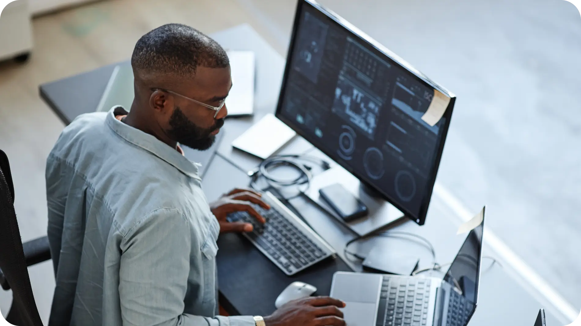 IT professional working on a computer with multiple screens displaying data analytics, representing data security and system management.