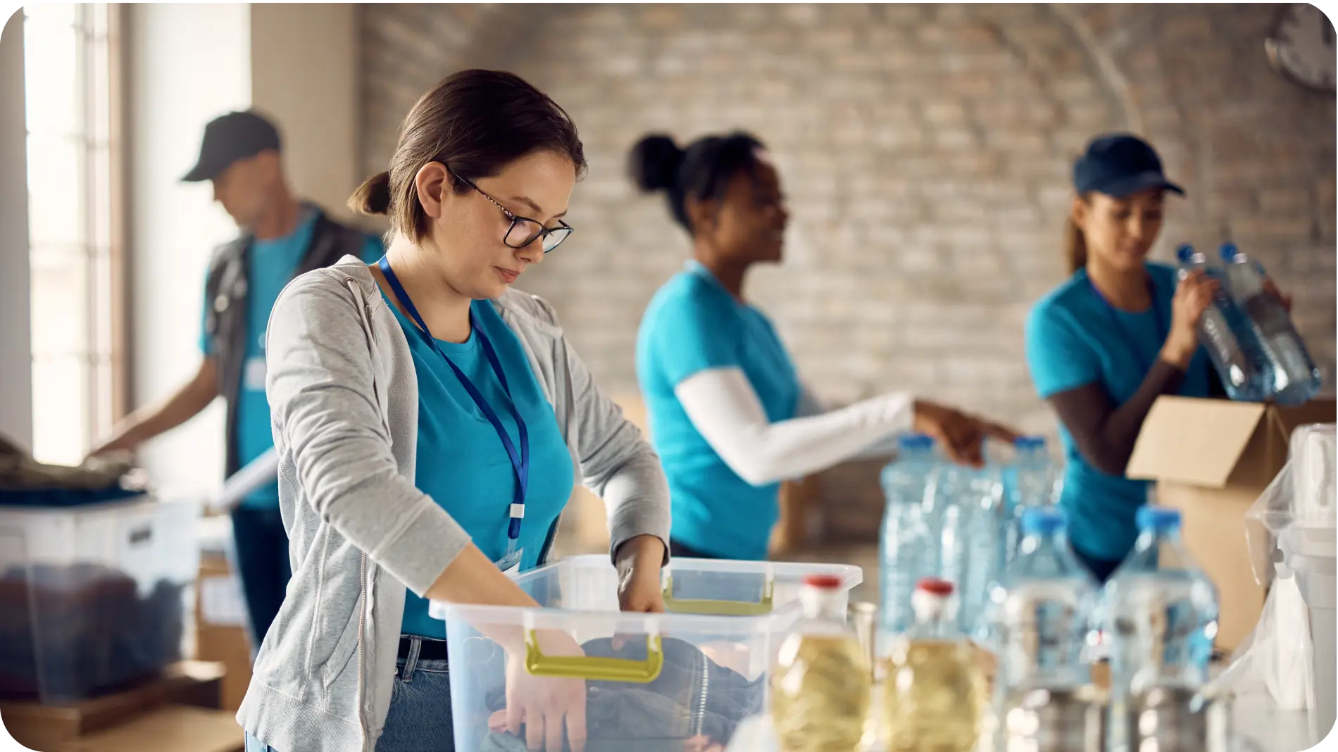 Volunteers in blue shirts working together in a donation center, sorting supplies and packing items for distribution.