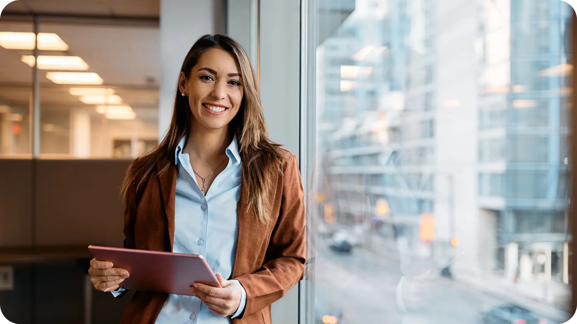 Woman smiling to camera holding a tablet.