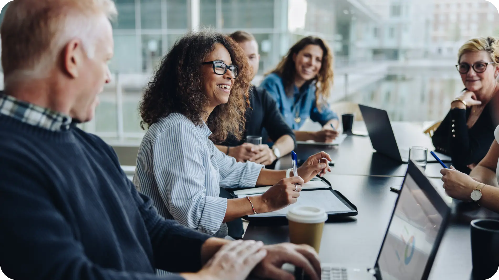 Team of professionals collaborating in a meeting, smiling and discussing strategies, representing effective risk mitigation and teamwork.