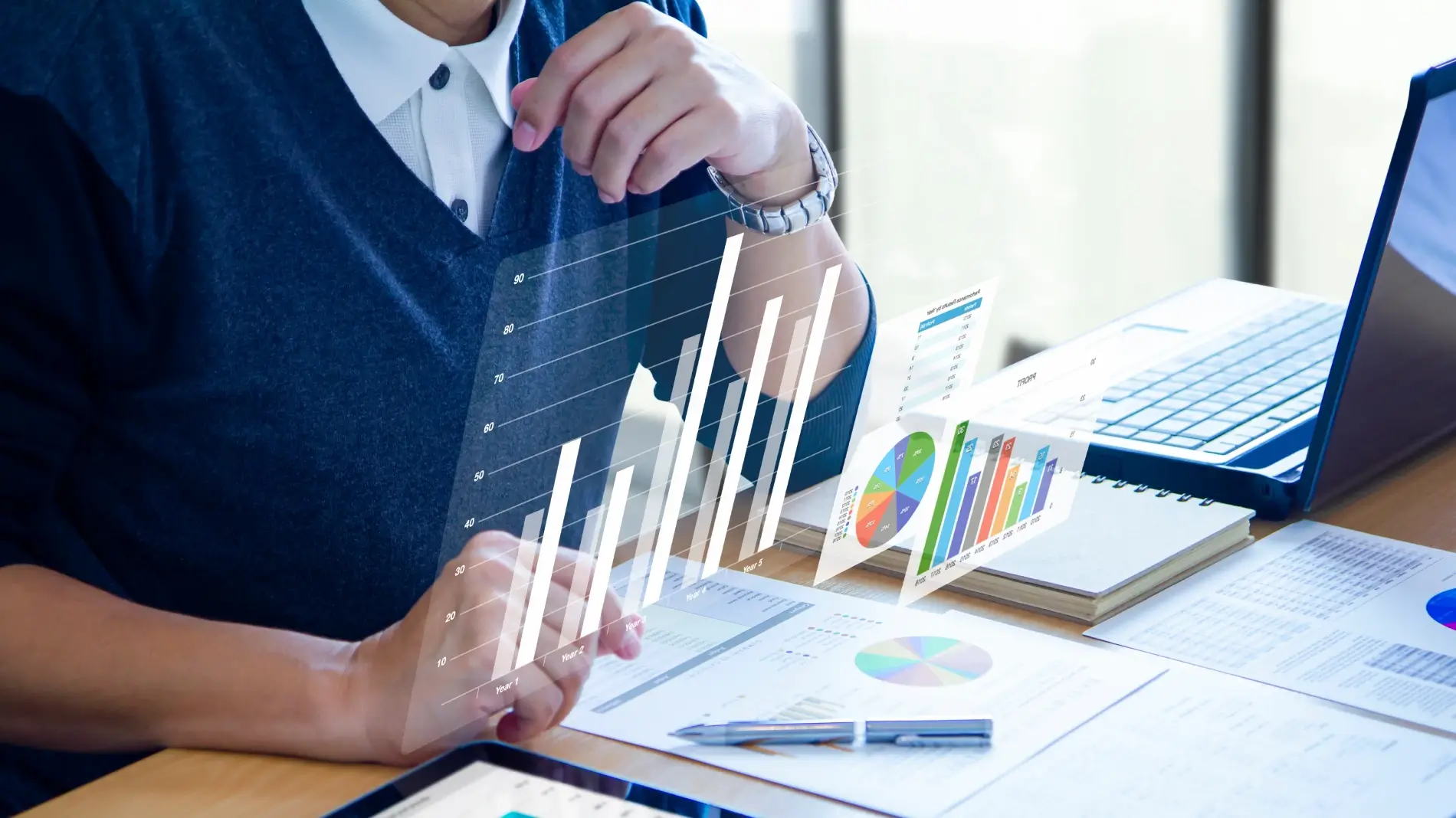 Man sitting in front of laptop with papers and a visual graph.