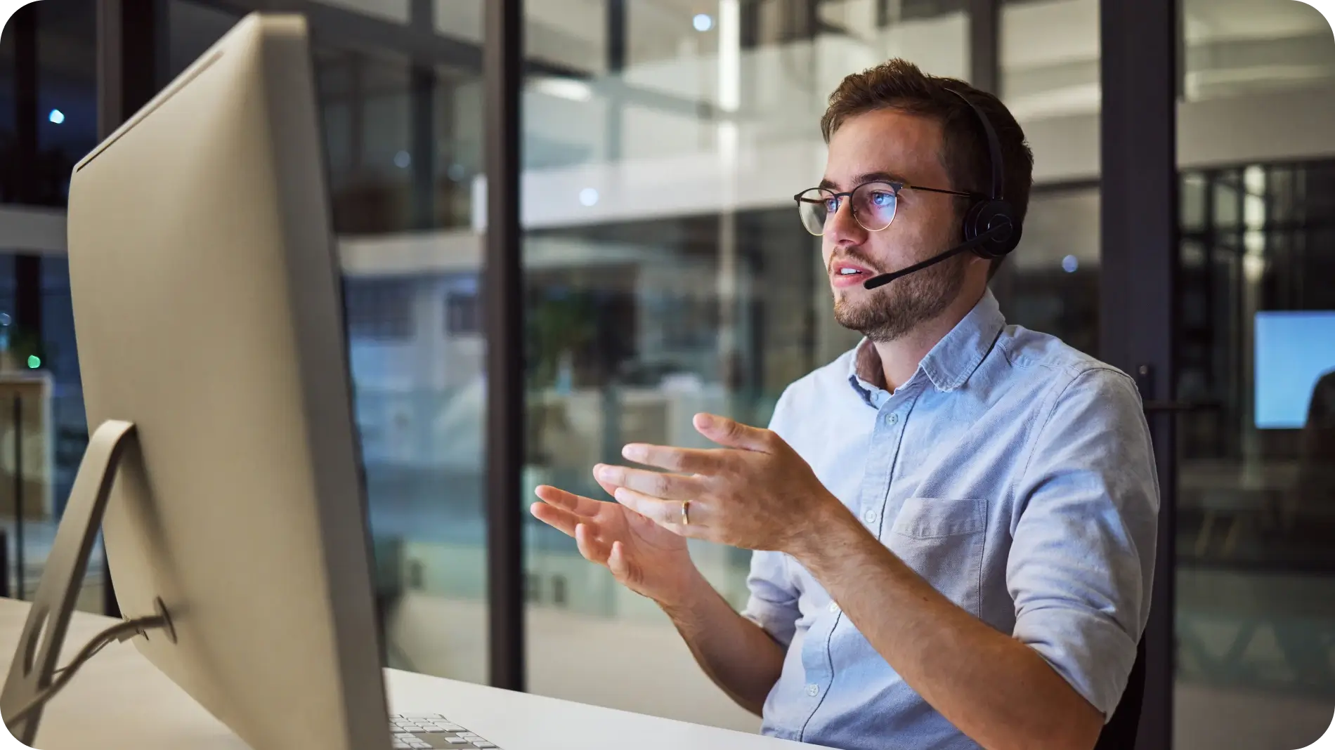 Man sitting with headset in front of laptop talking to a client.