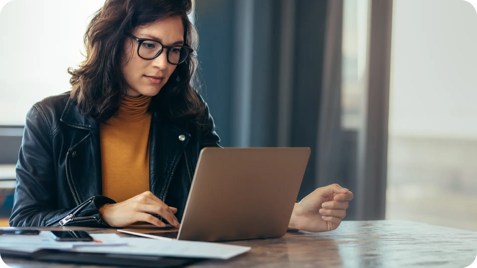Woman wearing glasses sitting in front of a laptop.