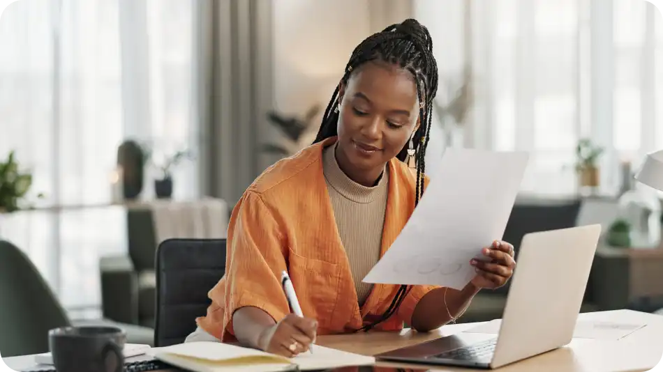 Woman sitting in office with a piece of paper in her hand, writing notes.