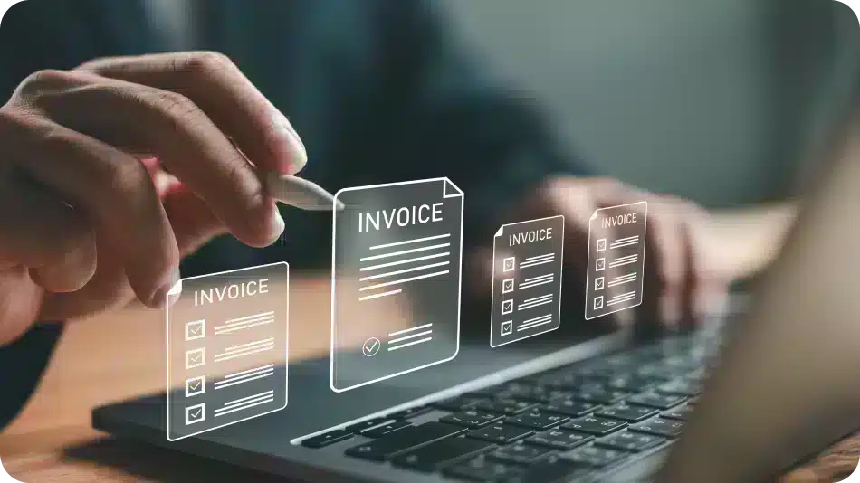 Person using a laptop with digital invoice icons hovering above the keyboard.